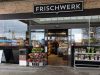 Eingang einer FRISCHWERK Filiale mit Blumen vor dem Store
