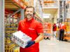 Lagerarbeiter in Logistikhalle trägt Getränkedosen